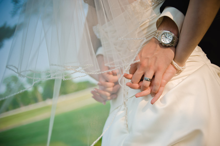 groom and bride holding hands with veil in wind