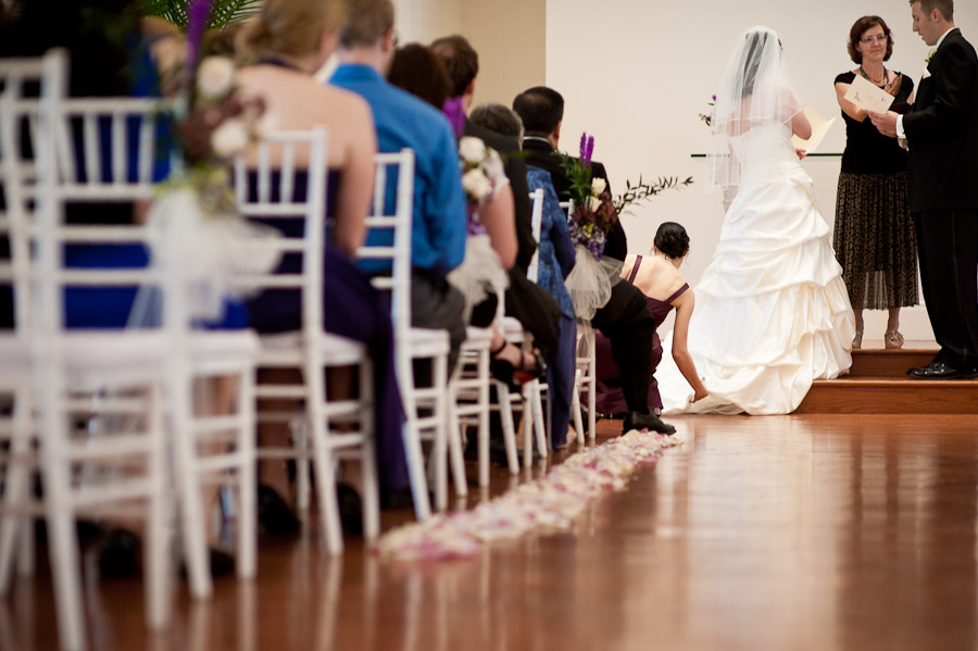 bridesmaid adjusting wedding gown during ceremony