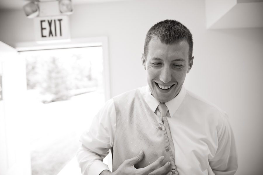 groom putting on vest before indianapolis wedding