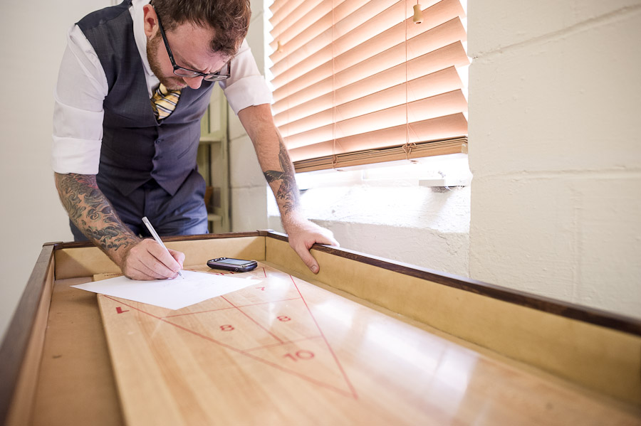 Cool groom writing vows on shuffleboard table in Louisville, KY