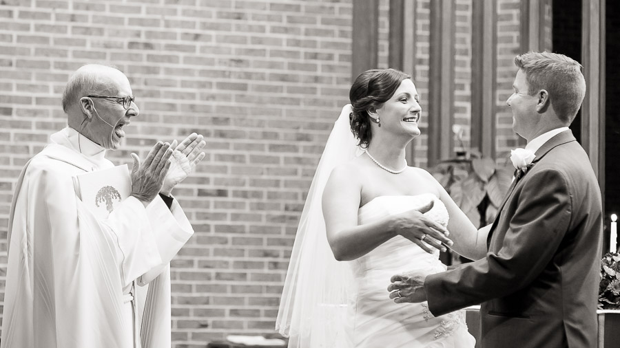 Very happy priest and newly married couple at Christ the King church