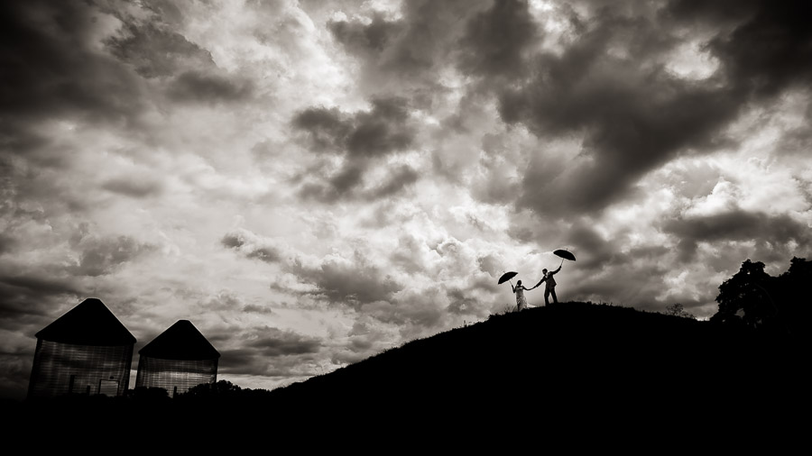 Dramatic, cloudy, windy, wedding day portrait with umbrellas by TALL + small Photography