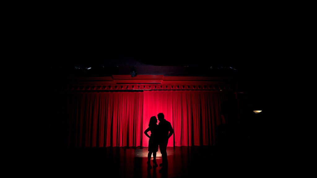 Rachel + Travis spotlit at a theater