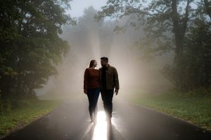 Couple backlit in the fog walking towards camera during their Shenandoah National Park engagement photography