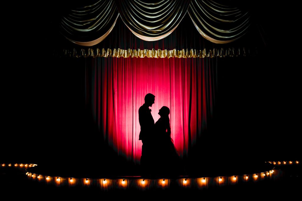 Backlit silhouette of bride and groom on the stage at the Yellow Barn wedding venue at Shenandoah Caverns