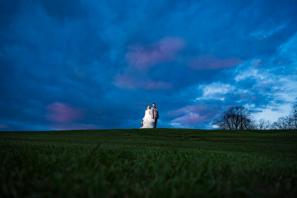 Bride and Groom spotlit on a hill minimalistically at Castle Hill Cider