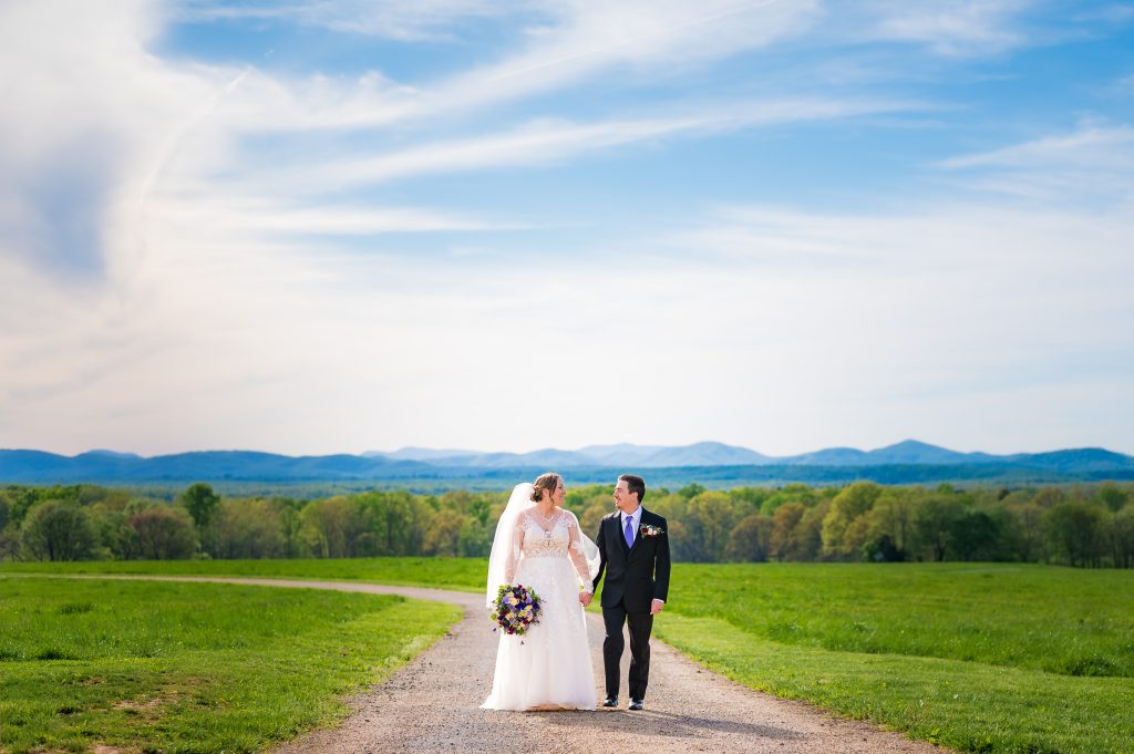 Couple walking down the road at the Mt. Ida Barn and Vineyards Black Branch Ceremony Site with mountains behind them