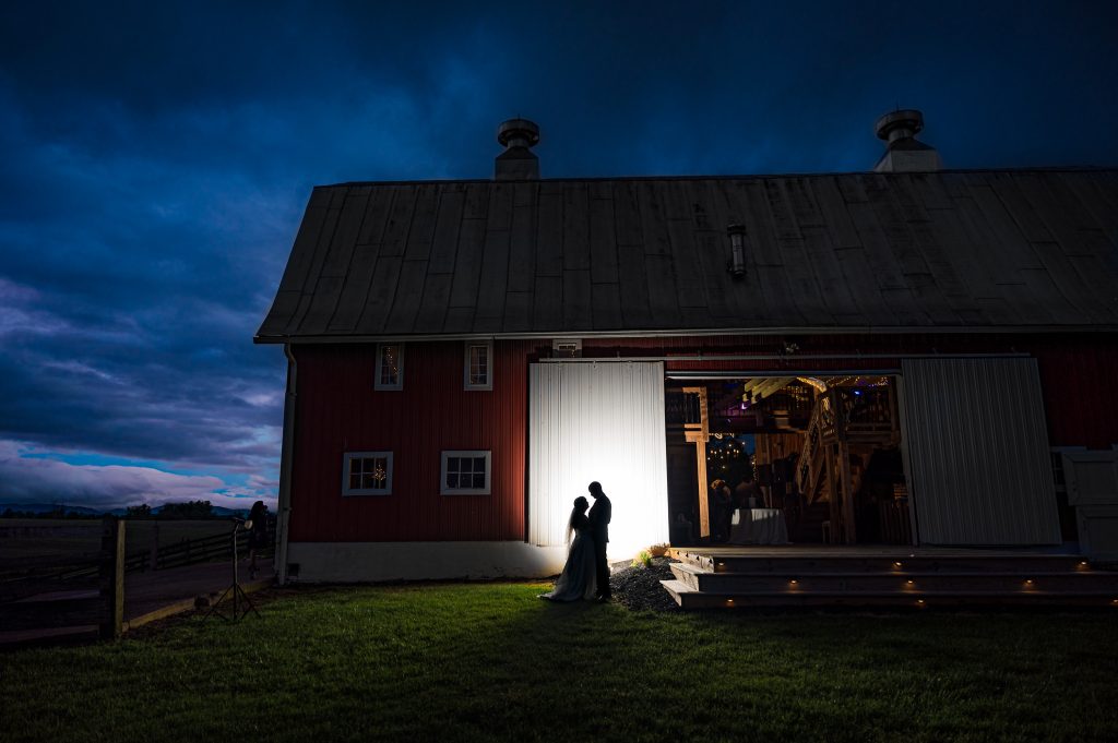 Silhouette of bride and groom against the barn at night at Rivercrest Barn and Event center in Elkton, VA