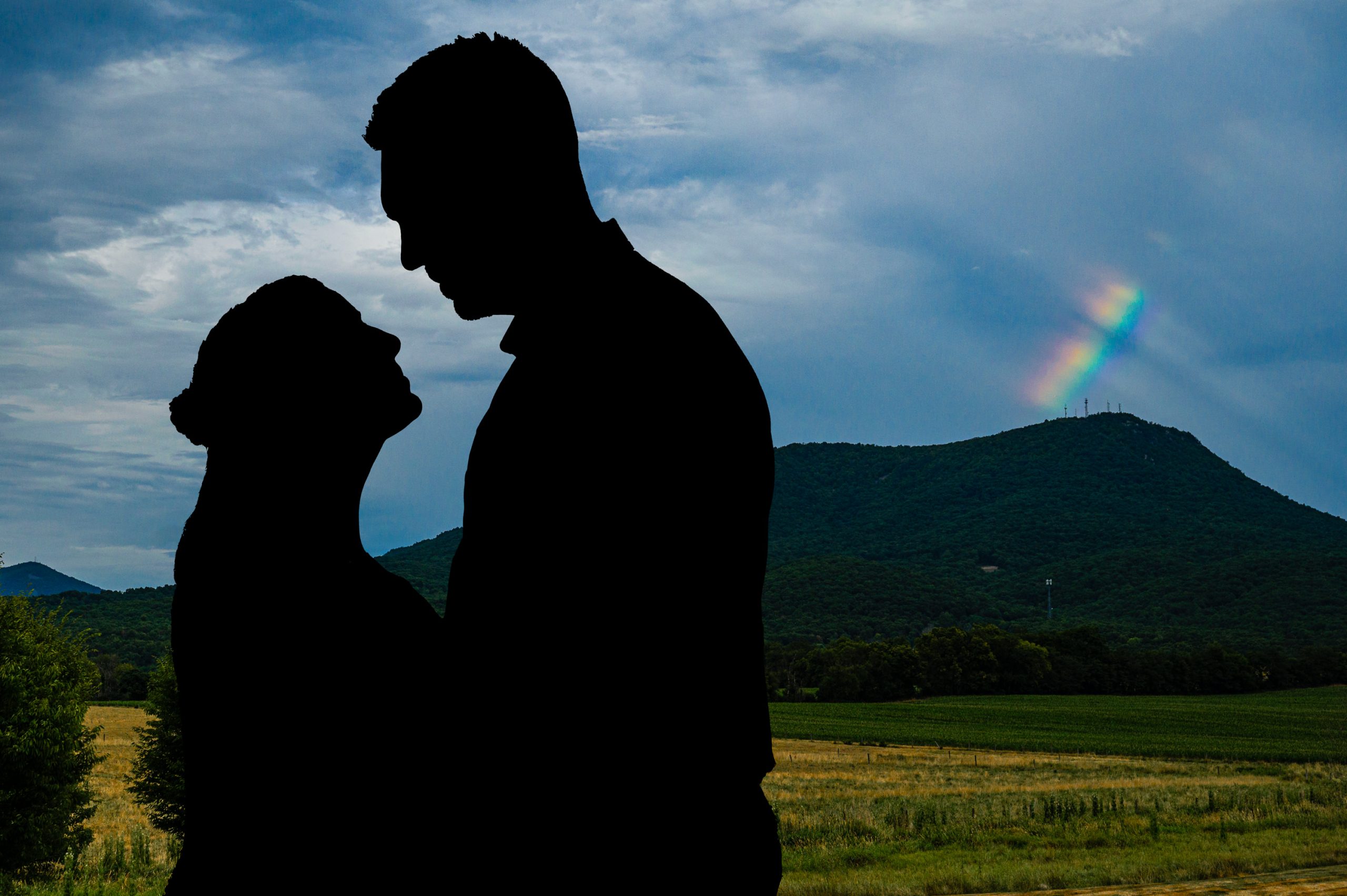 Silhouette of couple with a rainbow over Massanutten mountain at their Cross Keys Barn wedding